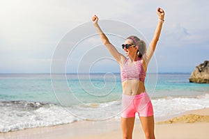 Fit woman on the beach feeling excited