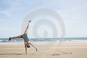 Fit woman cartwheeling on the sand photo