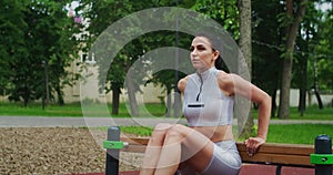 Fit woman do reverse push ups using bench in a Park in slow motion. Beautiful woman playing sports in the Park.