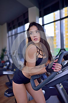 Fit woman doing cardio on bicycle trainer in a gym. Fitness, sport and lifestyle concept.