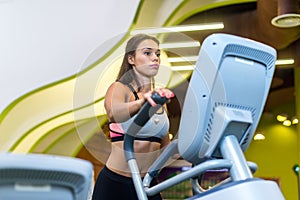 Fit woman doing cardio in an elliptical trainer in a gym.