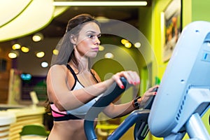 Fit woman doing exercise on a elliptical trainer.