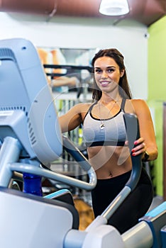 Fit woman doing exercise on a elliptical trainer.