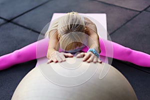 Fit woman doing exercise with fitness ball in club