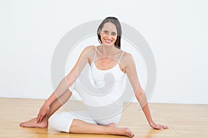 Fit woman doing the half spinal twist pose in fitness studio