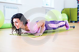 Fit woman doing plank exercise and push ups working on abdominal muscles triceps.