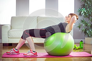 Fit woman doing sit ups on exercise ball