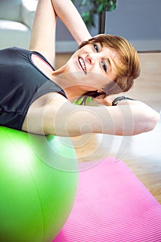 Fit woman doing sit ups on exercise ball