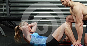 Fit woman doing sit ups with trainer