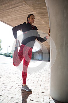 Fit woman doing stretching exercise with support of pillar