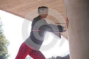 Fit woman doing stretching exercise with support of pillar