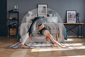 Fit woman doing stretching workout in morning at home. Downward facing dog yoga pose