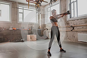 Fit woman doing workout with kettlebell in gym
