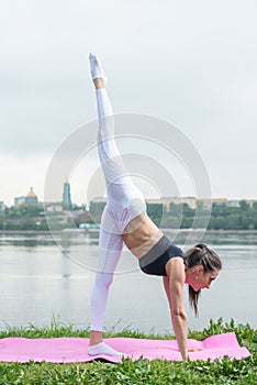 Fit woman doing yoga asana leg is lifted adho mukha svanasana downward facing dog.