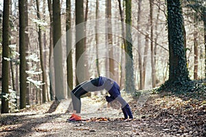 Fit woman doing yoga in forest.