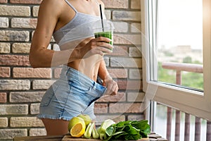 Fit woman drinking vegetable Green detox smoothie. raw food diet