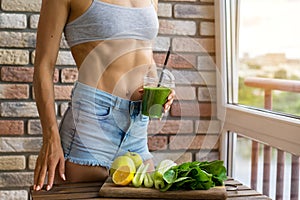 Fit woman drinking vegetable Green detox smoothie. raw food diet