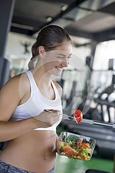 Fit woman eating healthy salad after workout