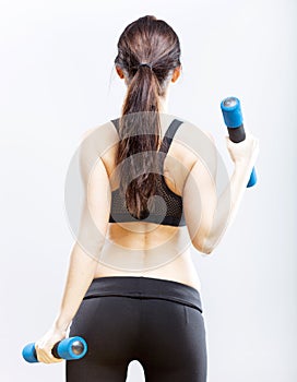 Fit woman during exercise with dumbbells, back view