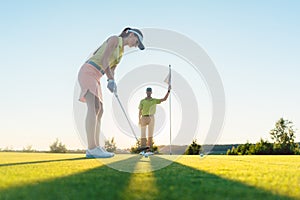 Fit woman exercising hitting technique during golf class with an