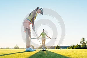 Fit woman exercising hitting technique during golf class with