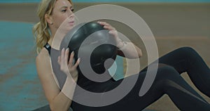Fit woman exercising with pilates ball at gym. Female athlete doing workout using medicine ball.