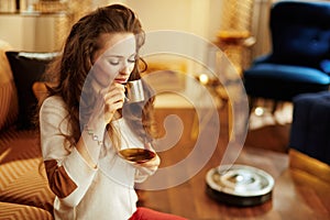 Fit woman having espresso while robot vacuum cleaning floor