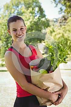 Fit woman holding bag of healthy groceries