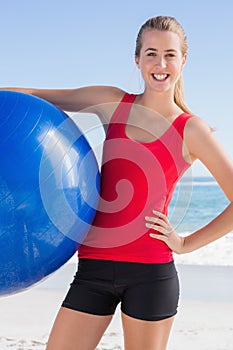 Fit woman holding exercise ball smiling at camera