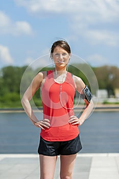 Fit woman jogger resting after run listening music. Smiling.