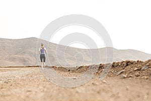 Fit Woman Jogging Into Distance Desert Dirt Road