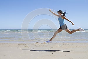 Fit woman leaping mid air on a beach