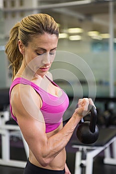 Fit woman lifting kettle bell in gym