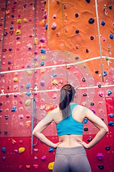 Fit woman looking up at rock climbing wall