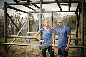 Fit woman and man standing against monkey bars during obstacle course