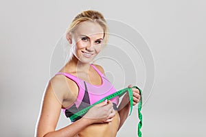 Fit woman measuring her chest breasts with tape measure