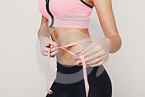 Fit woman measuring her waist closeup