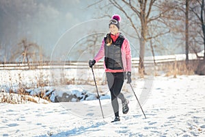 Fit woman Nordic walking in winter landscape