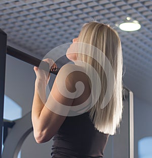 fit woman performing pull ups in a bar