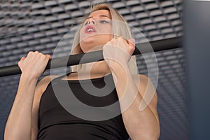 fit woman performing pull ups in a bar