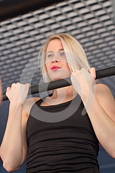 fit woman performing pull ups in a bar