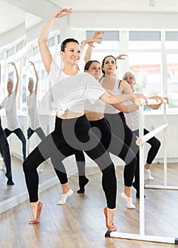 Fit woman performing wide squats at ballet barre in studio