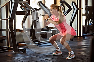 Fit woman in pink outfit working out at modern gym