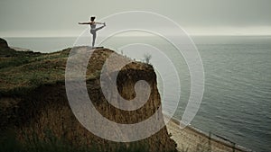 Fit woman practicing yoga asana on hilltop. Girl making gymnastic on beach.