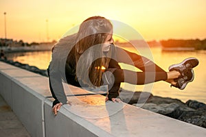 Fit woman practicing yoga, doing arm stand Astavakrasana, asymmetrical arm balance EightAngle Pose near the sea coast.