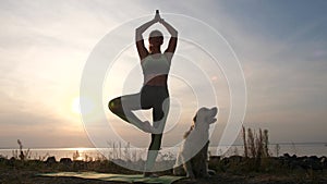 Fit woman practicing yoga on sea shore at sunset