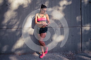 Fit woman runner checking smartwatch outdoors