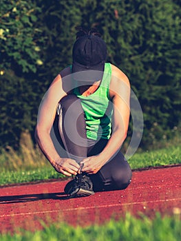 Fit woman runner tying shoelaces. Athletic woman run