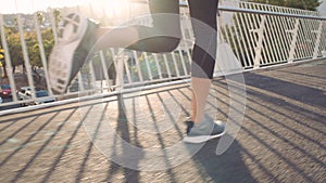 Fit woman running and jogging on a bridge in the city outdoors. Closeup on legs of a motivated and strong athlete