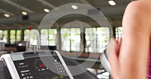 Fit woman running on treadmill with trainer timing her